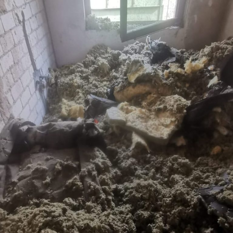 Ein Zimmer mit unordentlichem Boden, bedeckt mit Isoliermaterial und Schutt.